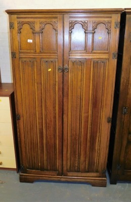 A mid 20thC oak two door wardrobe, each door profusely carved, 176cm high, 95cm wide, 54cm deep.