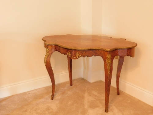 A 19thC kingwood walnut and rosewood marquetry topped serpentine centre table, with gilt metal mounts, 74cm high, 121cm wide, 76cm deep.