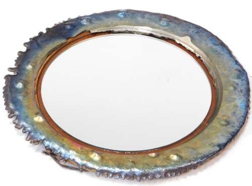 A modern wall art mirror, the outer metal frame in a multicoloured overlay finish in steel, with central mirror plate on a wooden backing, 63cm diameter.