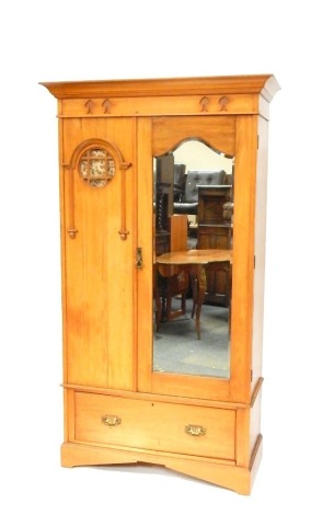 A Victorian Art Nouveau satin birch single wardrobe, the out swept pediment above a foliate carved frieze, single mirrored door, flanked to the left with a material backed circular pane panel, over one long frieze drawer, raised on bracket feet, 201cm hig