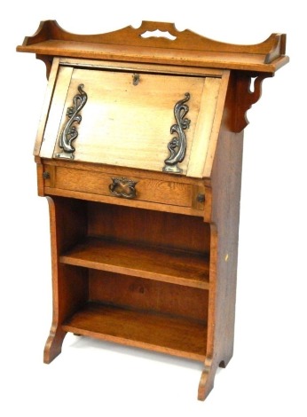 A Victorian Art Nouveau oak student's bureau, the three galleried top with broken pediment, over a fall flap with stylised copper strap work, above two shelves, raised on out splayed legs, 114cm high, 62cm wide, 36cm deep.