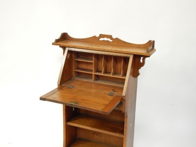 A Victorian Art Nouveau oak student's bureau, the three galleried top with broken pediment, over a fall flap with stylised copper strap work, above two shelves, raised on out splayed legs, 114cm high, 62cm wide, 36cm deep. - 2