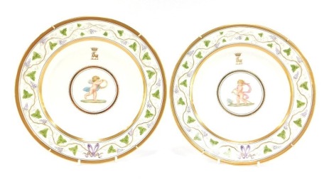 A pair of late 19thC Wedgwood porcelain plates, painted by J Thorley, with cherubs, one holding a staff and crosier, the other a ring, beneath a gilt crest of a goat beneath a coronet, believed to be Duke of Bedford crest, within a repeating vine border, 