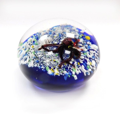 An art glass paperweight, decorated internally with an octopus, starfish and a shell, on a sea bed and blue ground, bears paper label to base, B2024, 8.5cm diameter.