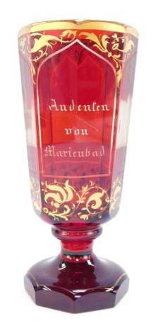 A Bohemian late 19thC ruby flashed glass vase, of octagonal footed form, 'Andenton von Marenbad', together with panels engraved with buildings, comprising Kreuzbrunn, Allesbadhaus, Ambrosinsbr., the ground over gilded with scrolling leaves, 19cm high.