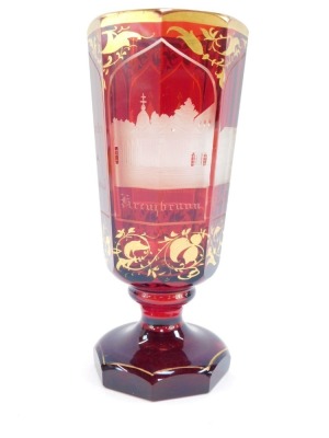 A Bohemian late 19thC ruby flashed glass vase, of octagonal footed form, 'Andenton von Marenbad', together with panels engraved with buildings, comprising Kreuzbrunn, Allesbadhaus, Ambrosinsbr., the ground over gilded with scrolling leaves, 19cm high. - 2