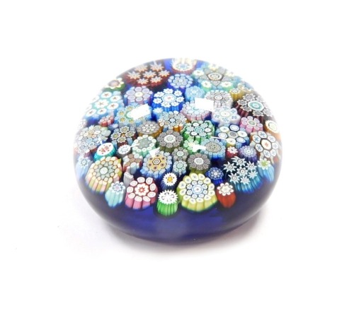 A Peter McDougall millefiori glass paperweight, blue ground with PMCD cane and paper label, 6cm diameter.