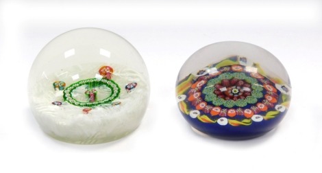 A 20thC millefiori and scrambled latticino paperweight, 8cm diameter, and a millefiori and candy cane paperweight, dark blue ground, 7.5cm diameter. (2)