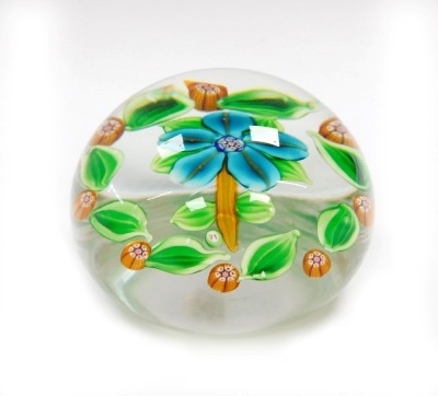 A Paul Ysart floral glass paperweight, decorated with a turquoise five petal flower, within a surround of green leaves and orange millefiori, PY cane, 7.5cm wide.