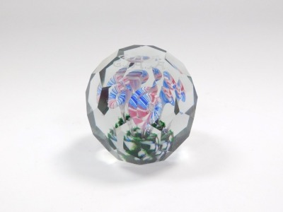 An early 20thC faceted glass paperweight, decorated internally with four glass stemmed flowers, on a green base, beneath initials 'G. A. A.', 9.5cm diameter.