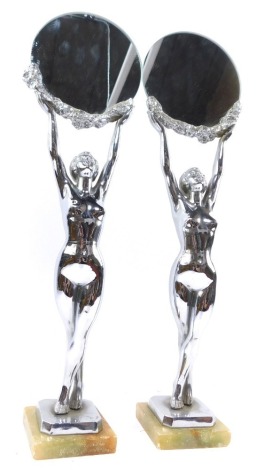 A pair of Art Deco chrome figural mirrors, formed as naked female figures holding aloft a garland and supporting a circular glass mirror, raised on an onyx base, stamped Limousin, 52cm high.