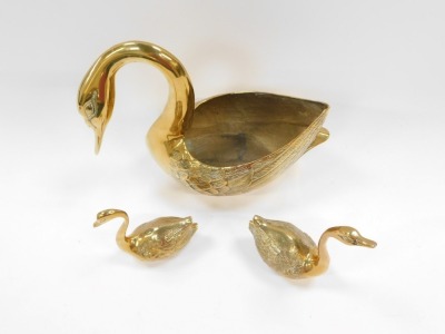 Three brass swan ornaments, comprising a large swan planter, with arch to neck, 25cm high, and two brass cygnet paperweights, 19cm high and 14cm high respectively. (3) - 2