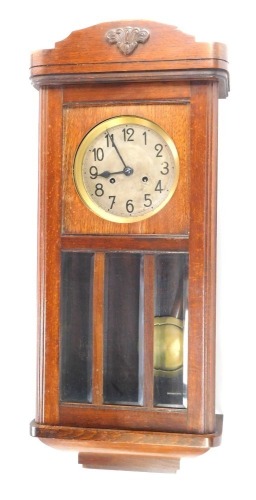 An oak wall clock, with silvered numeric dial and eight day movement, with fleur de lys crested top, above three glazed panel door, 80cm high, 32cm wide, 13cm deep.