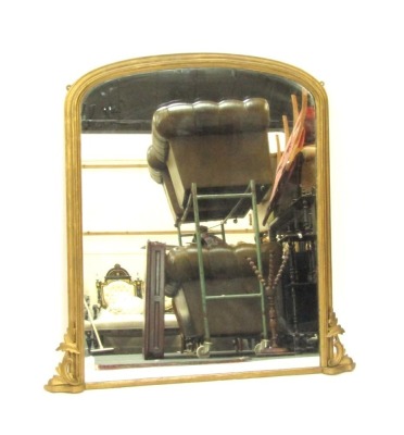 A Victorian giltwood overmantel mirror, the arched top with scroll leaf supports to each side, on bevelled mirror plate, 129cm x 105cm. (AF)