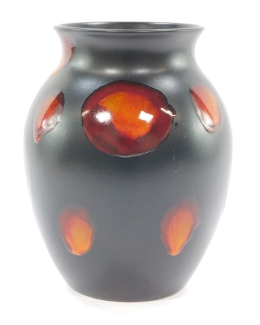 A Poole Pottery Galaxy vase, on a black ground with orange lustre streaks, 23cm high.