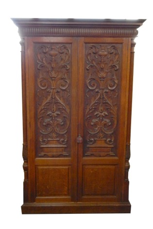 A Continental carved oak armoire, with moulded cornice, on reeded column supports, with urn floral field carved doors, 212cm high, 118cm wide, 42cm deep.