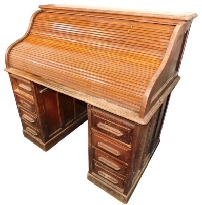 An Edwardian oak roll top writing desk, with S shape tambour, opening to reveal fitted sections above two pedestal each with three drawers, 124cm high, 125cm wide, 72cm deep.