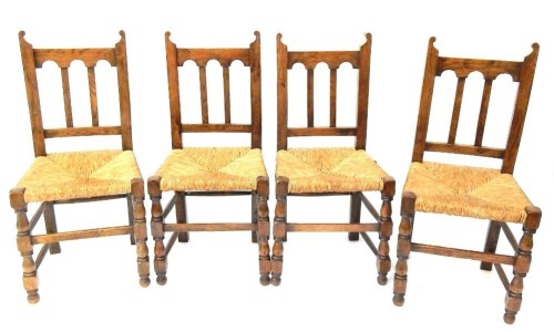 A set of four reproduction oak rush seated dining chairs, each with turret back and rush seat.