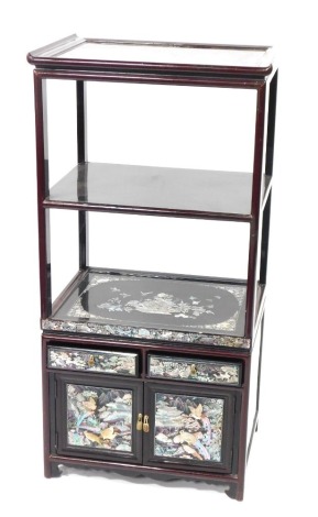 An Eastern hardwood side cabinet, with a shaped and moulded tray top above two shelves, with mother of pearl inlay with two short drawers and two cupboard doors, in a red lacquered overall finish, 100cm high, 49cm wide, 36cm deep.