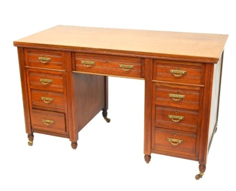 An Edwardian oak writing desk, with arrangement of four drawer pedestals and single central door, on tapered and reeded legs, terminating in castors, 73cm high, 120cm wide, 57cm deep.