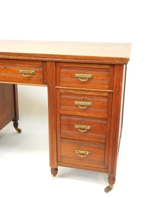 An Edwardian oak writing desk, with arrangement of four drawer pedestals and single central door, on tapered and reeded legs, terminating in castors, 73cm high, 120cm wide, 57cm deep. - 2