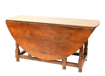 An early 18thC oak gate leg table, with oval top, two drop leaves on a turned base, 76cm high, 159cm wide, 165cm deep.