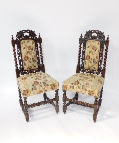 A pair of early 20thC carved oak hall chairs, with leaf carved and moulded back, barley twist column supports, with cream upholstery, 115cm high.