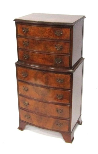 A reproduction burr walnut bow front chest on chest, each with three drawers with brass pierced back plate handles, on bracket feet, 114cm high, 51cm wide, 38cm deep.