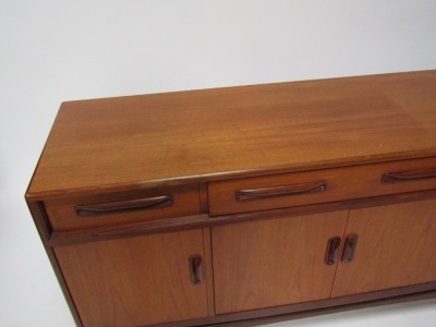 A teak mid century sideboard, with two short and one long drawer, above four cupboard doors on shaped supports, 88cm high, 150cm wide, 45cm deep. - 2