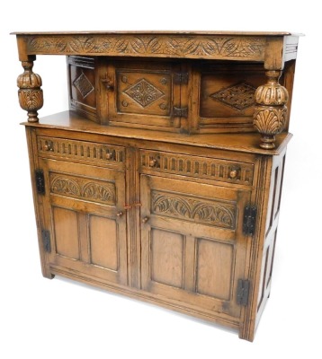 A carved oak court cupboard, the shelf top with single cupboard door, on bulbous finials, above two long drawers and cupboard base, 144cm high, 140cm wide, 45cm deep.