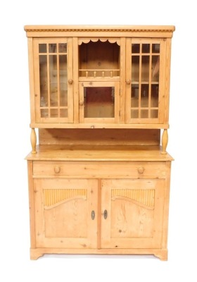 A stripped pine kitchen dresser, the top with three glazed doors, above base with arrangement of one long drawer and two cupboard doors, on bracket feet, 182cm high, 113cm wide, 48cm deep.