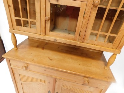 A stripped pine kitchen dresser, the top with three glazed doors, above base with arrangement of one long drawer and two cupboard doors, on bracket feet, 182cm high, 113cm wide, 48cm deep. - 2