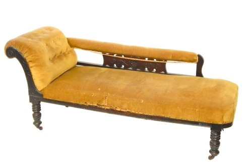 A Victorian mahogany and stained beech chaise longue, with carved drop arm and mustard coloured upholstery, terminating in castors, 145cm wide, 57cm deep, 64cm high.