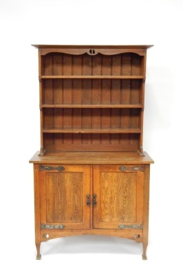 An Art Nouveau oak dresser, the pierced design cornice above an arrangement of three shelves and two cupboard base, with hinges on dart moulded feet, 187cm high, 107cm wide, 47cm deep.