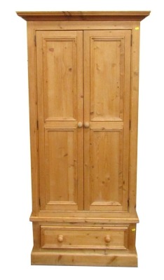 A stripped pine single wardrobe, with moulded cornice above two cupboard doors and single drawer base, on block base, 190cm high, 90cm wide, 65cm deep.