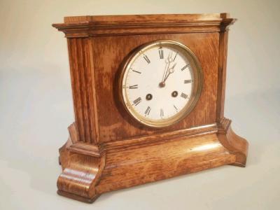 An oak cased early 20thC mantel clock with circular enamel dial with roman numerals