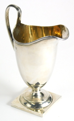 An Edward VII silver cream jug, with helmet shaped body, strap work handle and square foot, London 1906, 15cm high, 4oz.