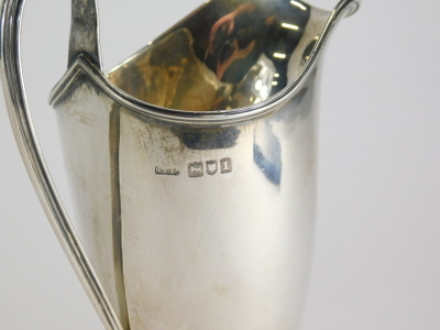 An Edward VII silver cream jug, with helmet shaped body, strap work handle and square foot, London 1906, 15cm high, 4oz. - 2