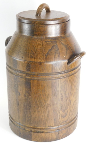 A 20thC oak milk churn, with C scroll handles and removable lid, 55cm high.