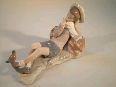 A Lladro figure of a boy resting and talking to a bird