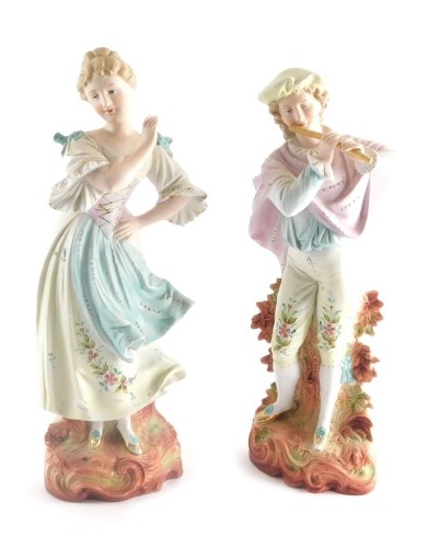 A pair of early 20thC Austrian bisque figures, of a lady and gentleman each dressed in finery, on scroll bases, 38cm high.