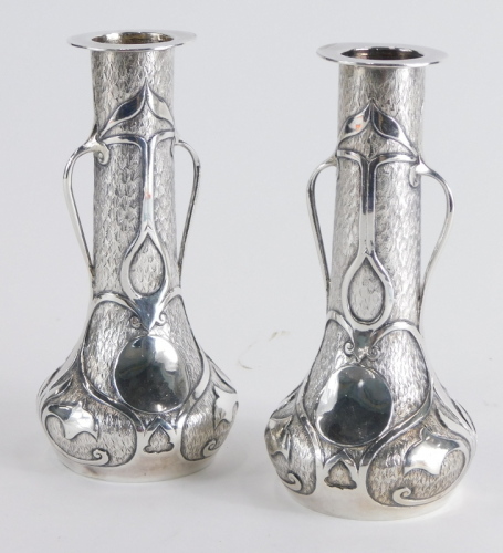 A pair of Art Nouveau vases, with cylindrical stems, bulbous bodies and a blind fret decoration with lotus flowers, on circular feet marked 95 white metal, 16cm high. (2)