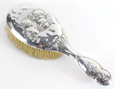 A Victorian silver hairbrush, repousse decorated with cherubs, London 1900, 25cm long.