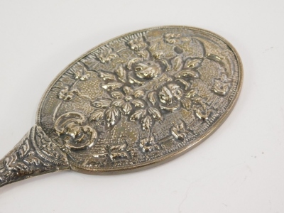 A 20thC hand mirror, heavily repousse decorated with flowers and scrolls, with plain bevel glass, 24cm long. - 2