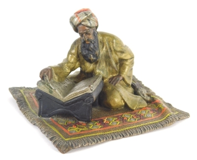 A 20thC cold cast bronze figure, of an Arabian gentleman seated on a carpet reading, in the manner of Bergmann, unmarked, 9cm wide.