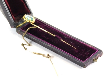 An Edwardian stick pin, with turned stem and floral top, claw set with an aquamarine coloured stone, 9cm high. (boxed)