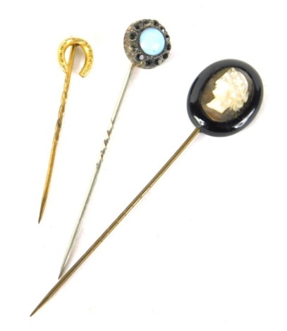 An early 20thC stick pin, with partial turned stem and horseshoe top, 4cm high, another with cameo, and a further stick pin. (3)