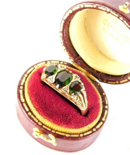 A 9ct gold dress ring, claw set with three green stones and a partial textured shank, 4.7g all in. (cased)