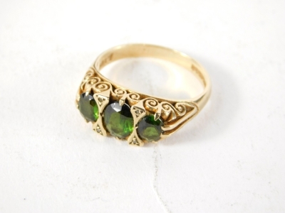 A 9ct gold dress ring, claw set with three green stones and a partial textured shank, 4.7g all in. (cased) - 2