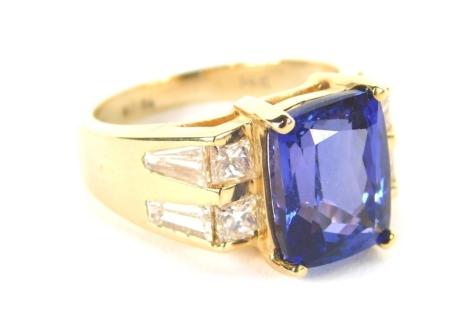 A tanzanite and diamond dress ring, the rectangular faceted tanzanite in four claw setting, 10.6mm x 7.8mm x 4.8mm, flanked by four square cut diamonds, each approximately 0.25ct and baguette cut diamond shoulders, yellow metal stamped 14k, the band marke